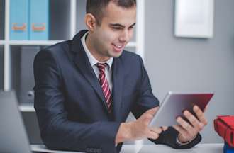 [Featured Image] A credit analyst works on a tablet in his office.  