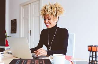 [Featured Image} A woman works on a laptop computer at a desk. 