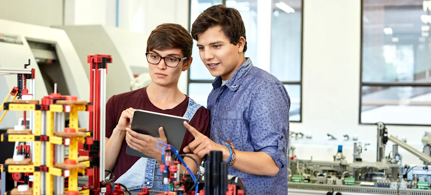 [Featured Image] Two people in STEM (what does stem stand for? Science, technology, engineering, mathematics) discuss their robotics project in a laboratory.
