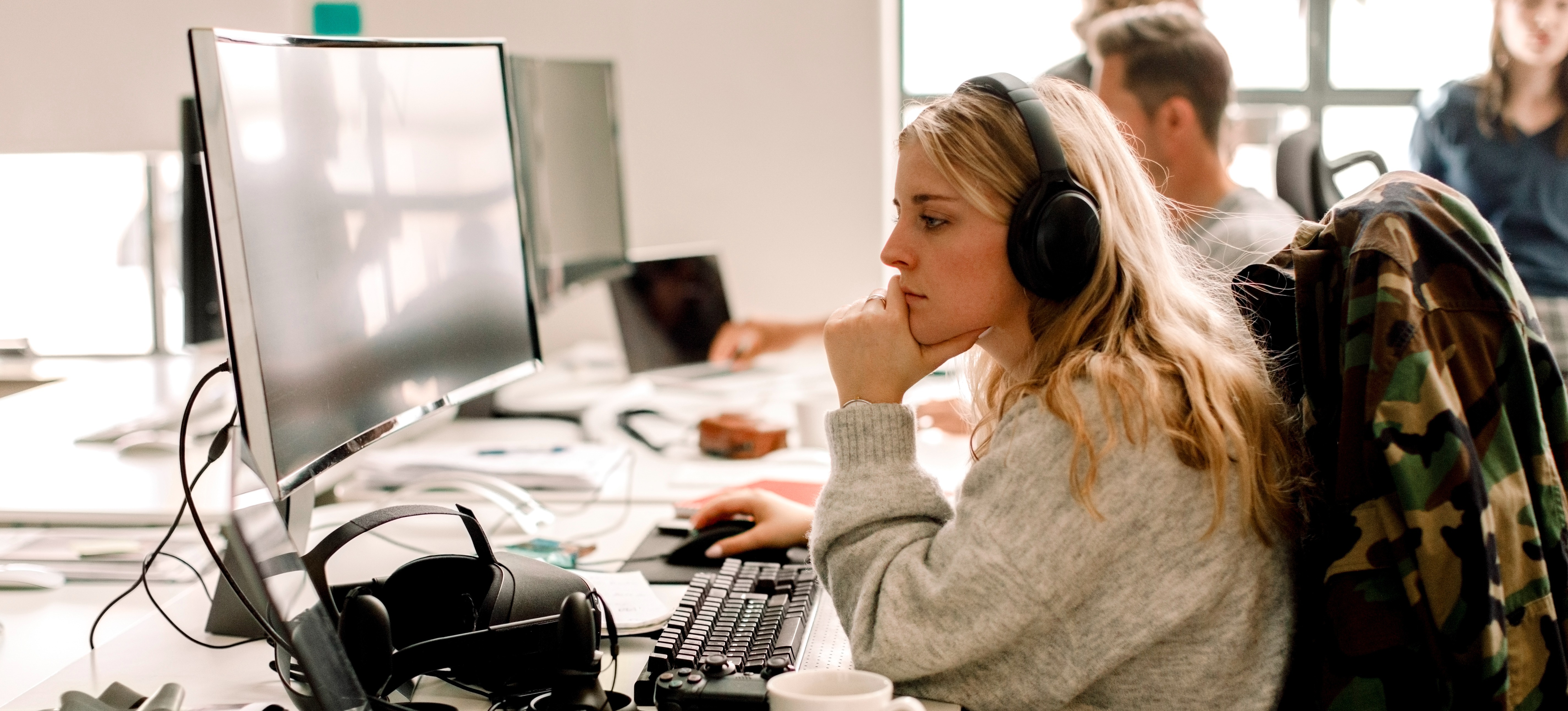 [Featured Image] A software developer wearing headphones works on a desktop computer. 