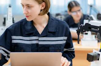 [Featured Image] A robotics engineer works on a project at their desk with a laptop and a robot model.