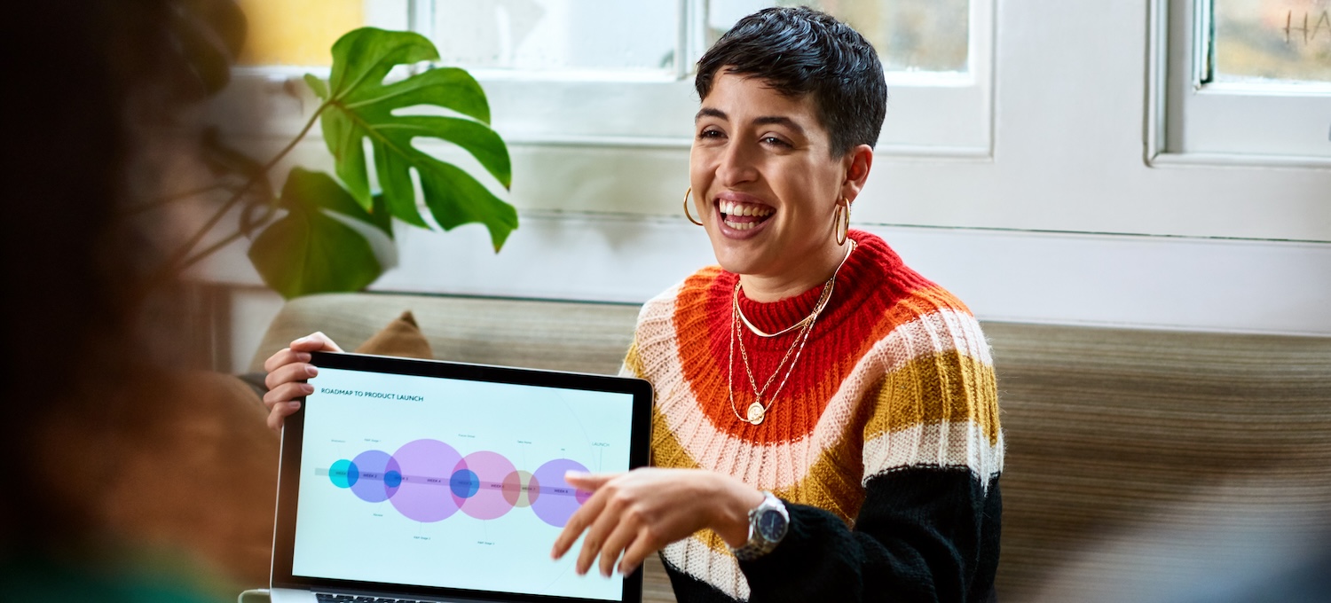 [Featured image] A young woman holds her laptop with a graph up. 