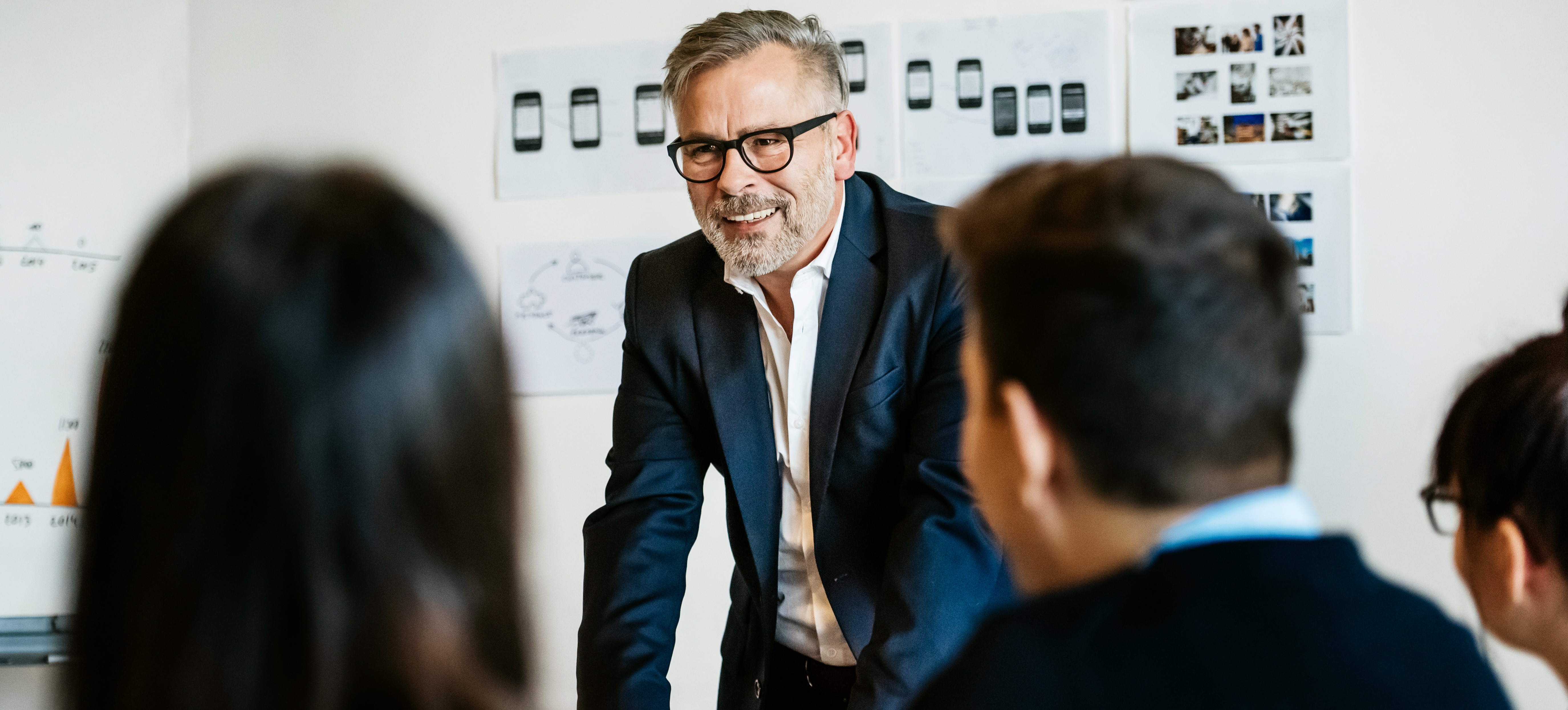 [Featured image] A senior professional addressing employees during a meeting.
