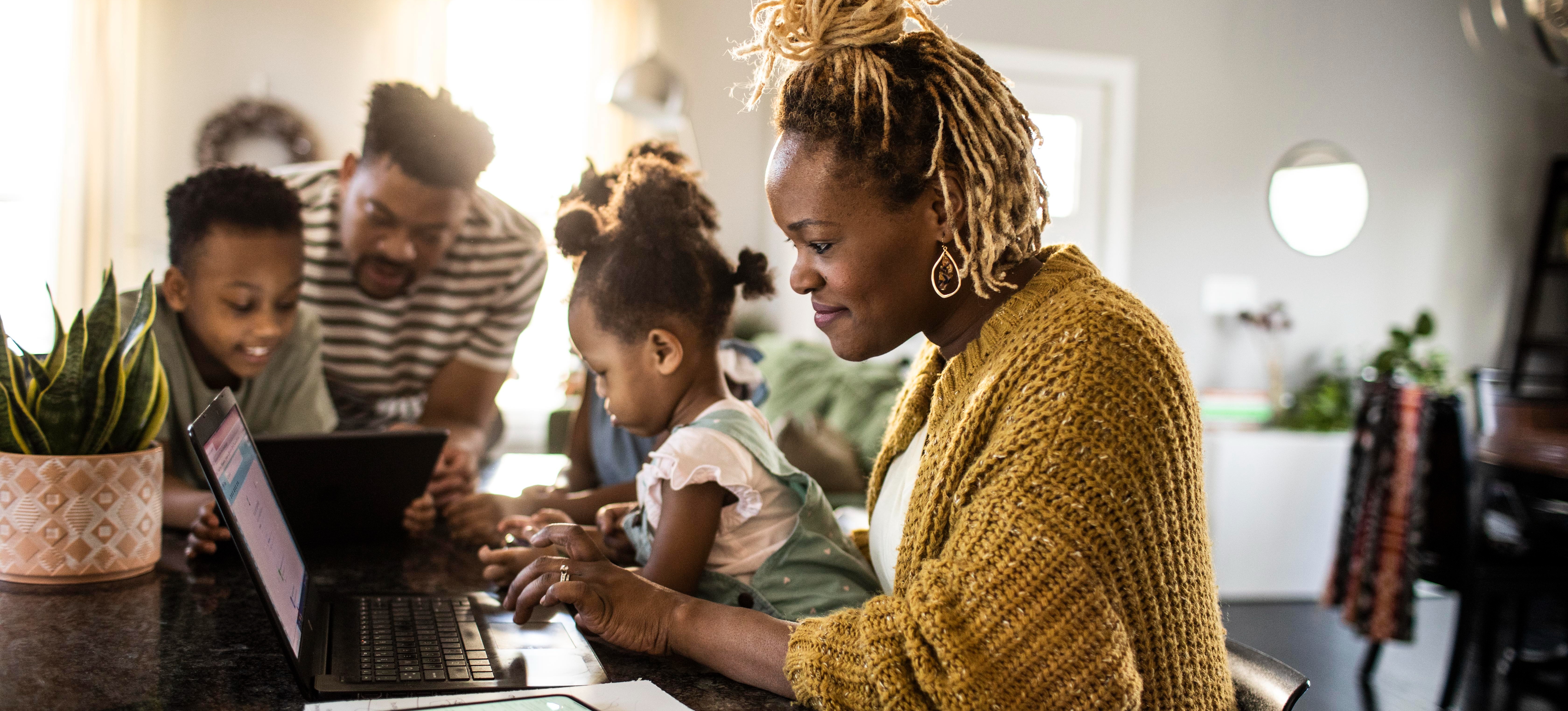 [Feature Image] A data management professional practices using SQL queries as part of their online coursework on a laptop at home with their family.