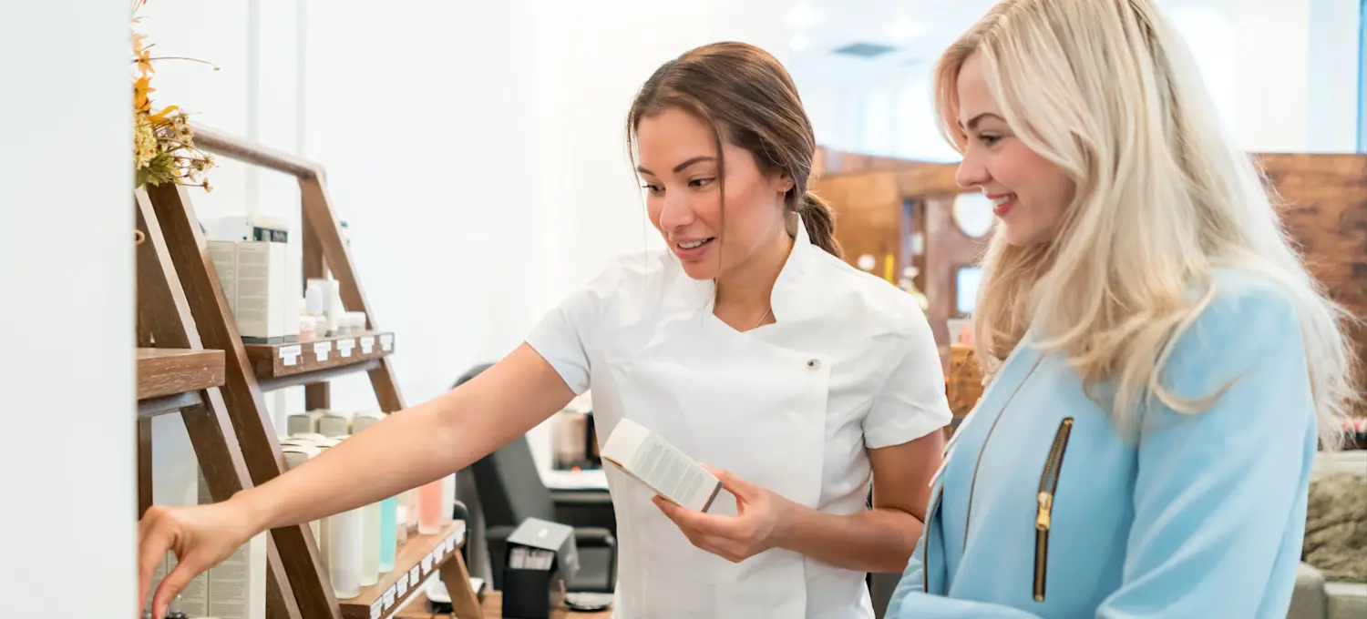 [Featured Image] A store owner shows products to a potential customer as they practices their sales techniques.