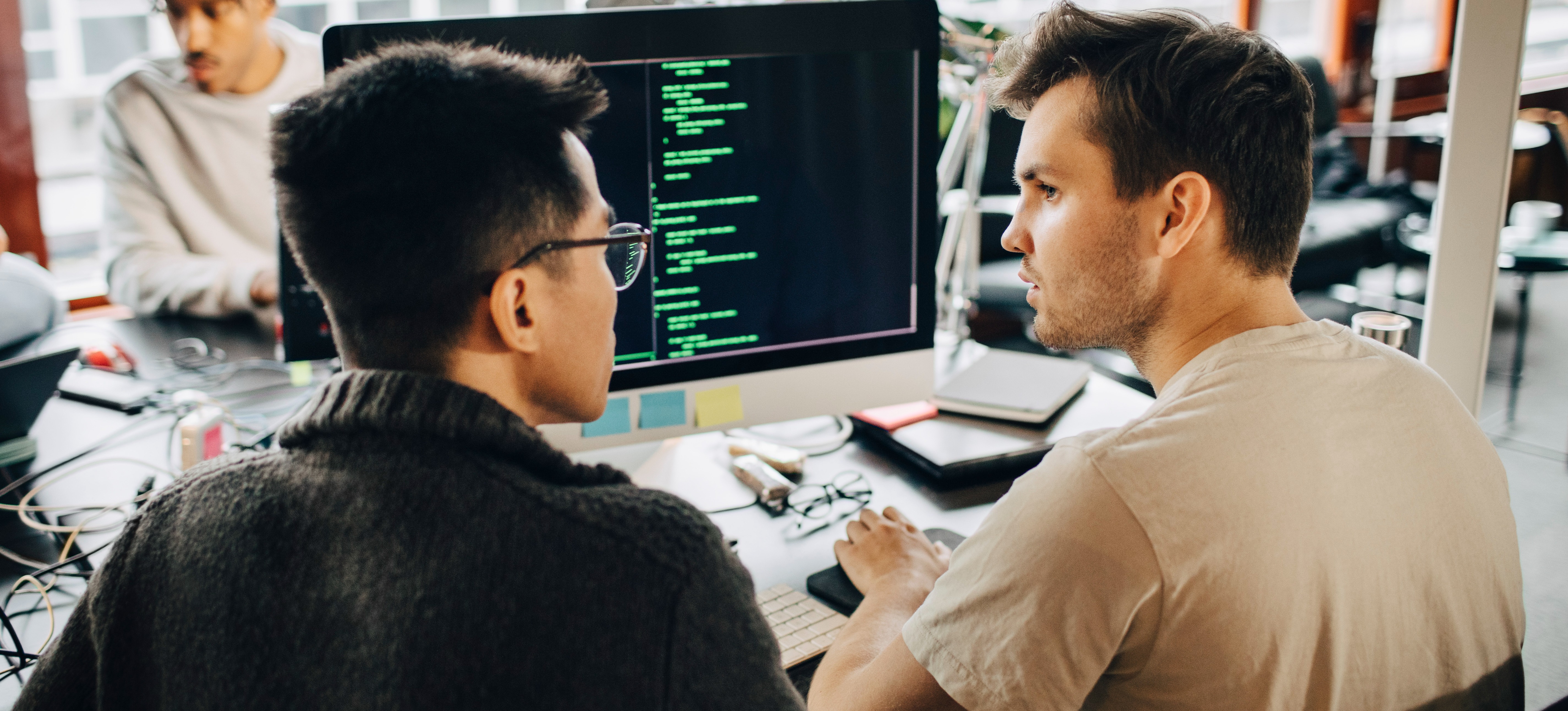 [Featured Image] Two programmers discuss the incredible capabilities of agentic rag while sitting in front of a computer in a shared office setting.
