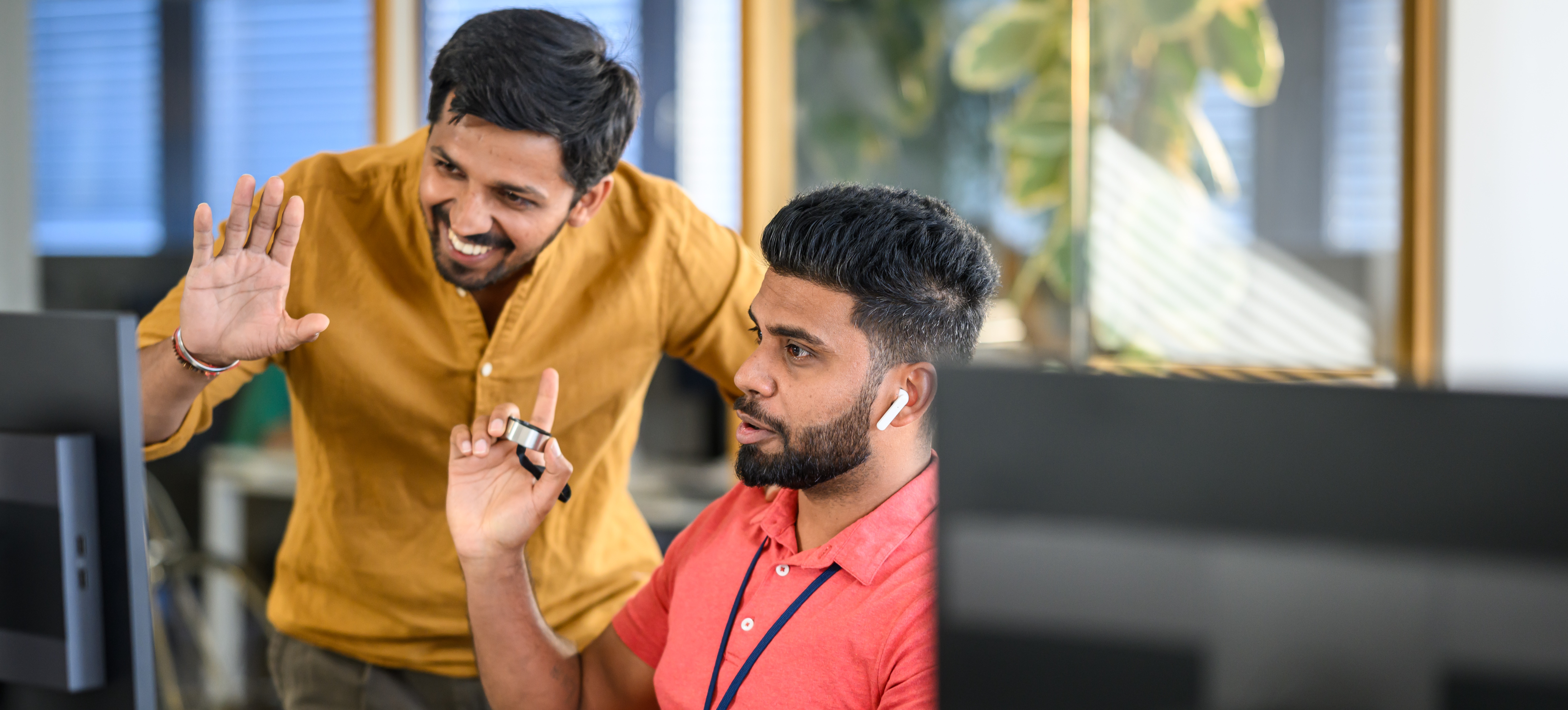 [Featured Image] Two cybersecurity professionals sit at a computer and talk about what hashing is and how they can use it to fix a problem. 