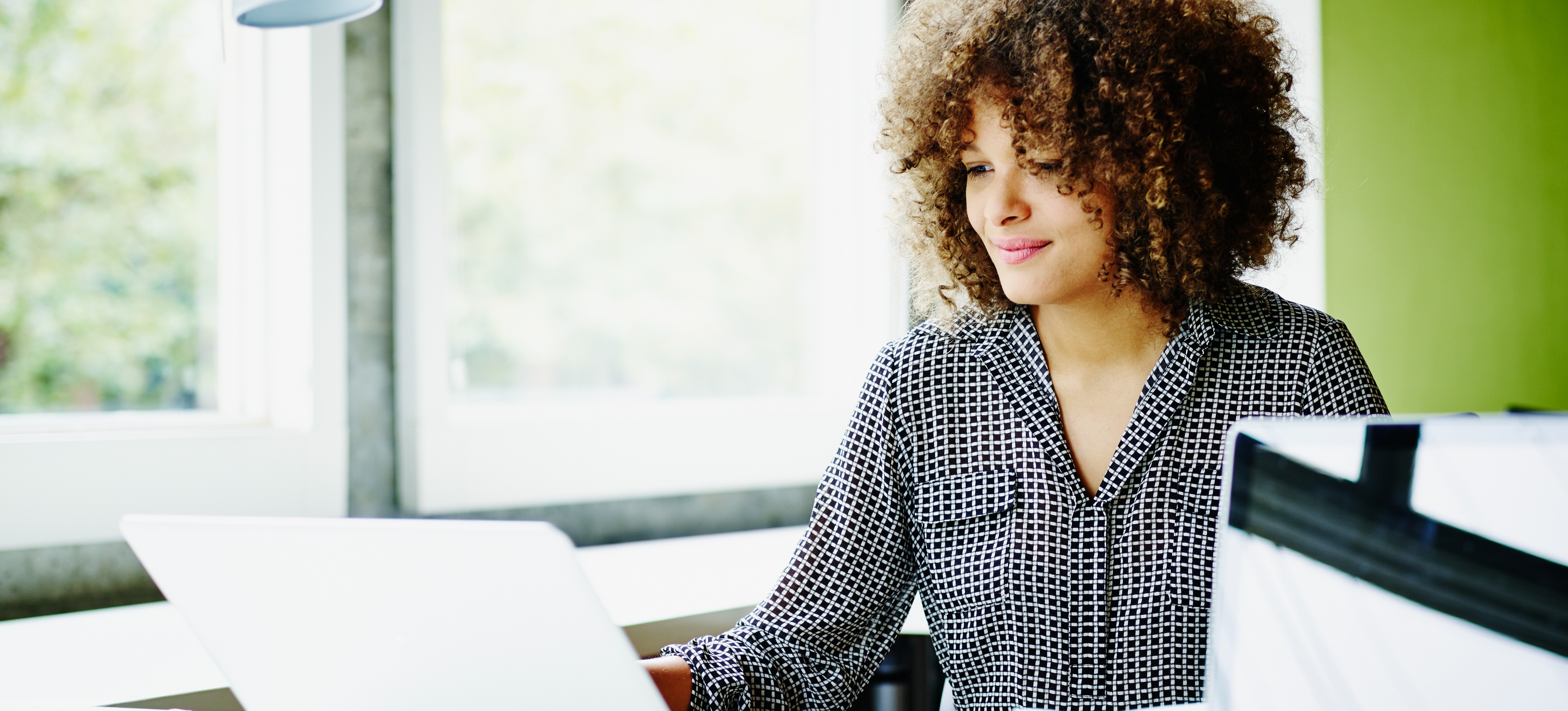 [Featured Image] A network analyst sits at a desk and uses a laptop to oversee their company's network operations.  