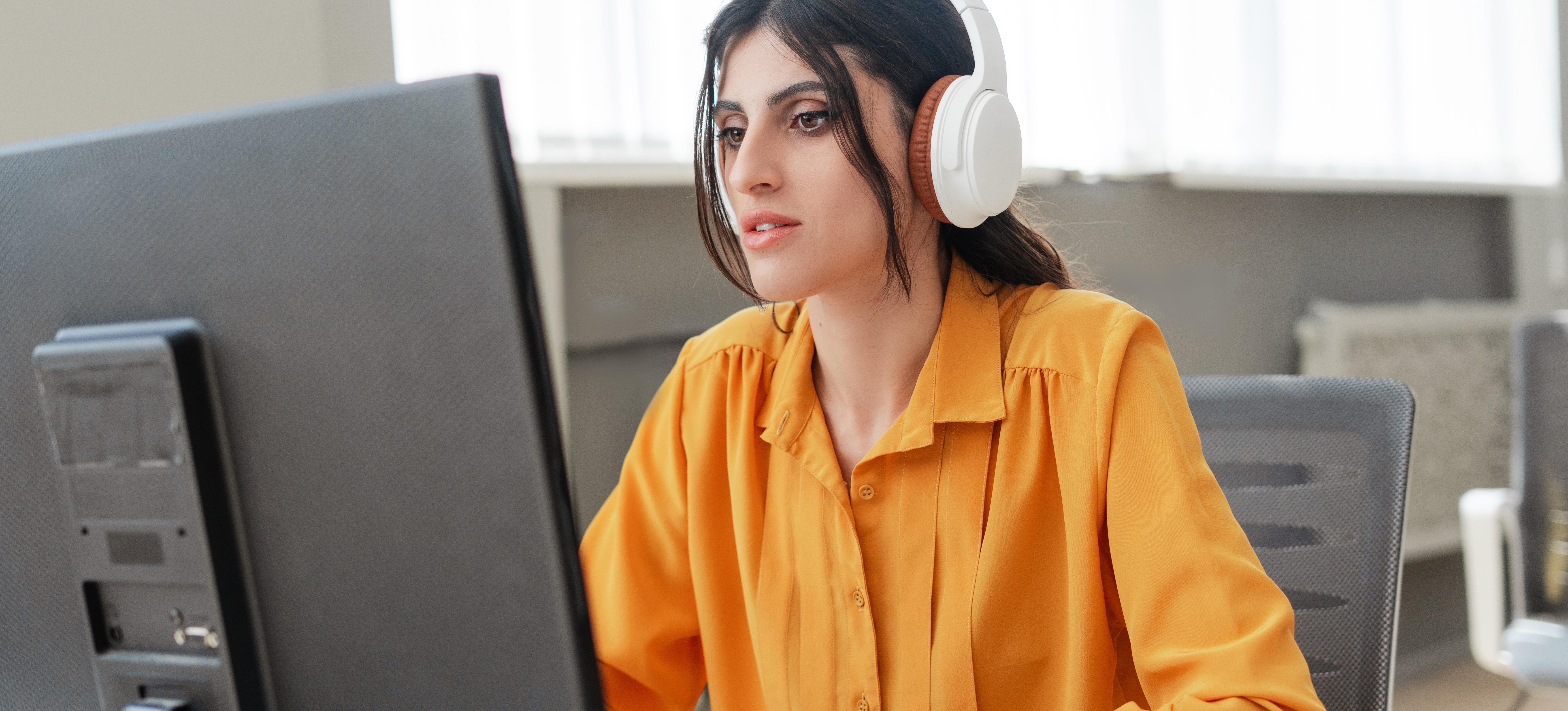 [Featured Image] A site reliability engineer wears noise-canceling headphones and focuses intently on a computer screen.
