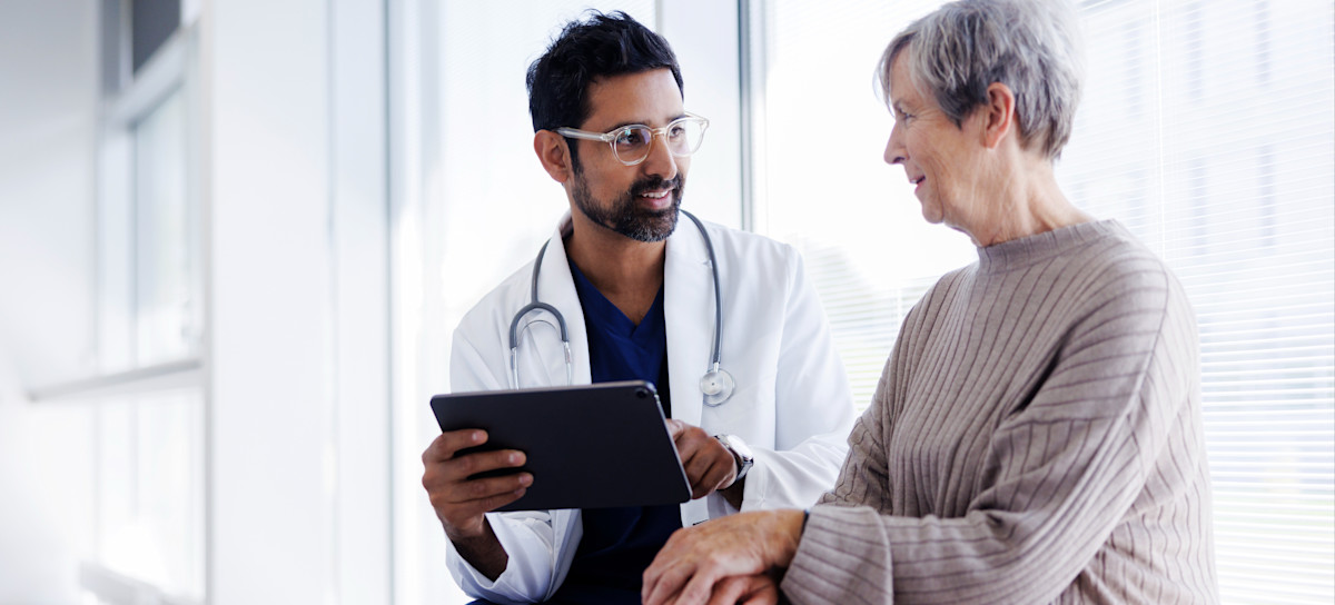 [Featured Image] A doctor and patient look at a digital tablet and they review the results of a recent test, which was interpreted in part using tools for artificial intelligence in medical diagnosis. 
