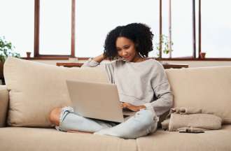 [Featured image] A woman works from home on her couch and uses Google Keyword Planner on her laptop.