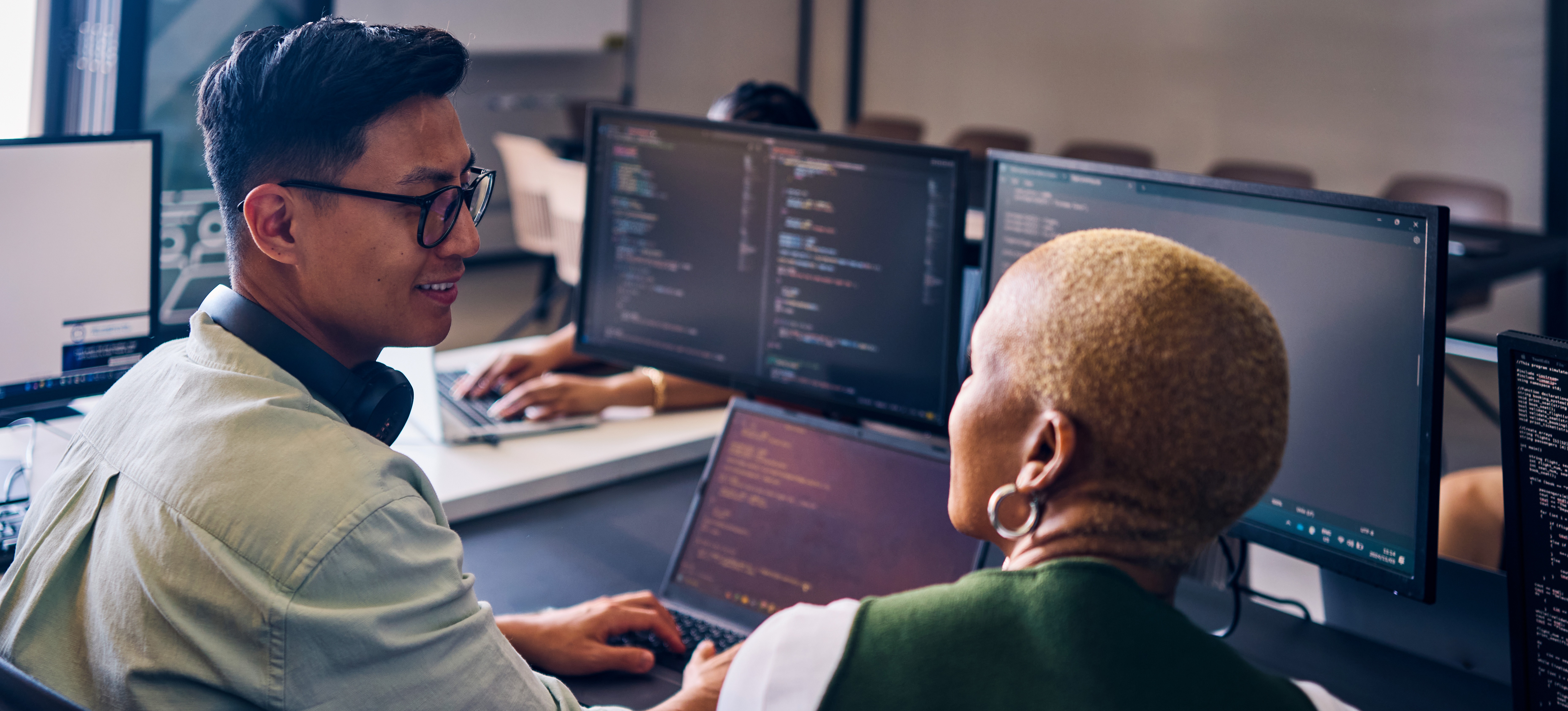 [Featured Image] Computer programmers working in a professional environment, focused on their computers displaying code, discuss the use of SciPy for scientific and mathematical computations in Python.
