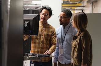 [Featured Image] A group of network administrators work at a computer while troubleshooting network issues.