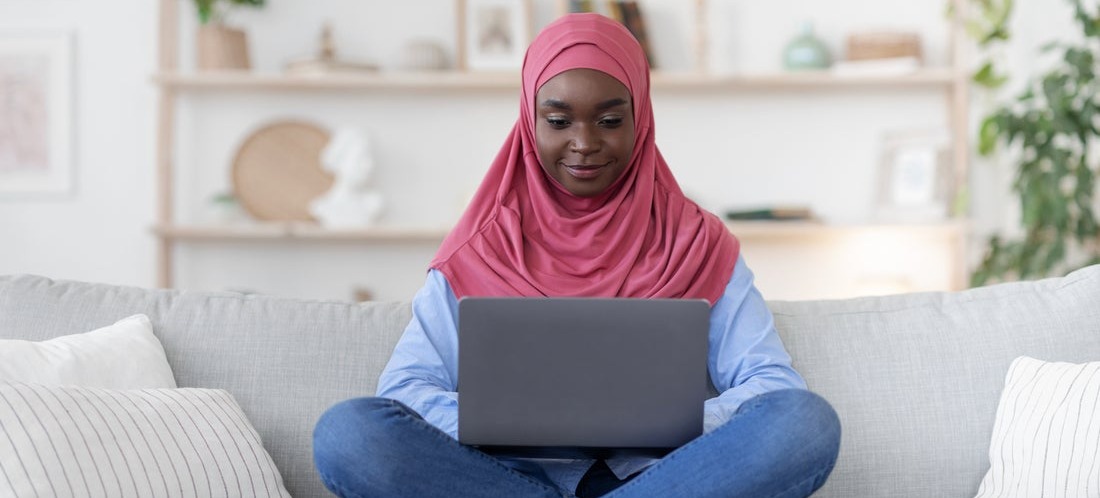 [Featured image] A person sits on their couch as they use their laptop to hide columns in Google Sheets.