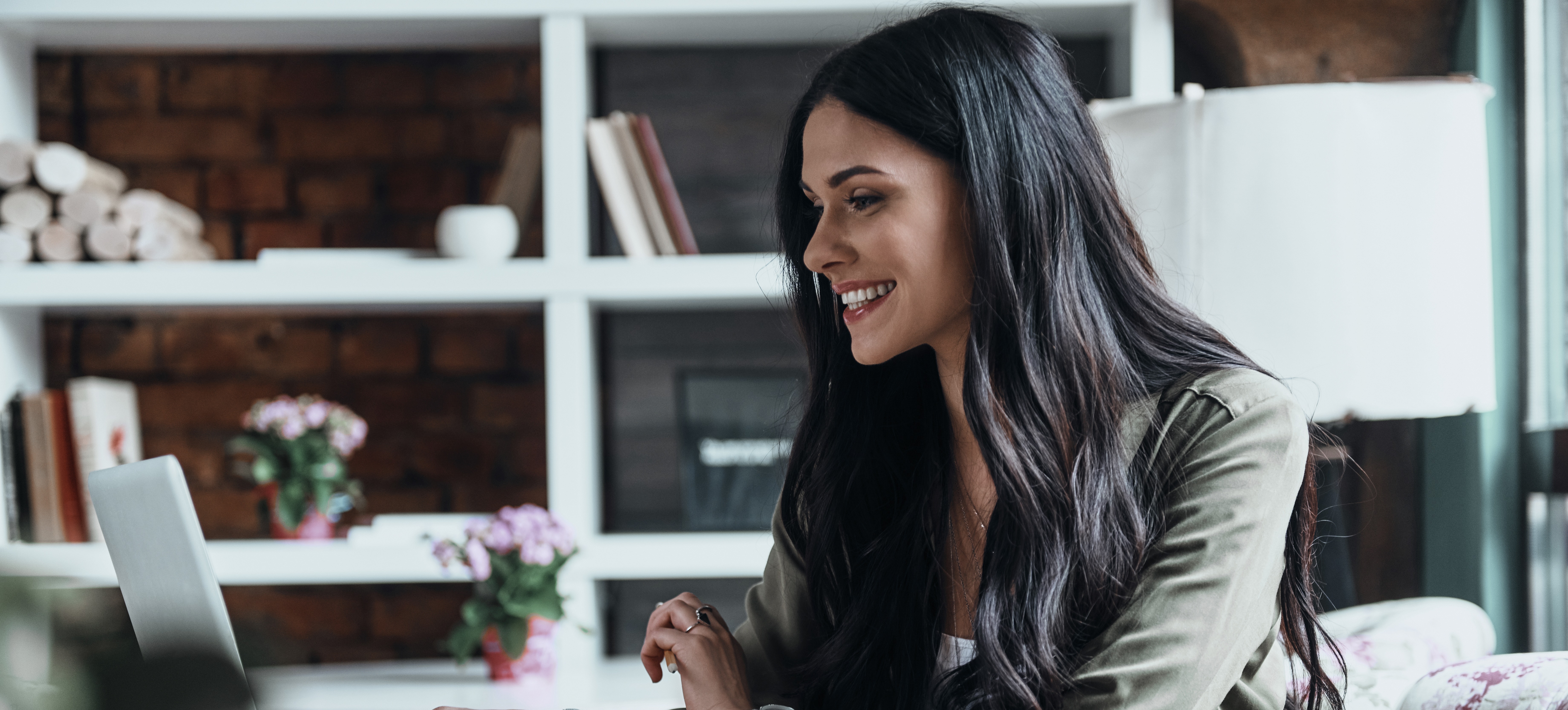 [Featured Image] A smiling marketing strategist researches the different types of email marketing on her computer in a sunny home office.

