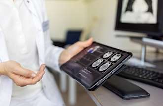 [Featured image] An IT support specialist in a health care facility works on connecting a tablet with a computer system.