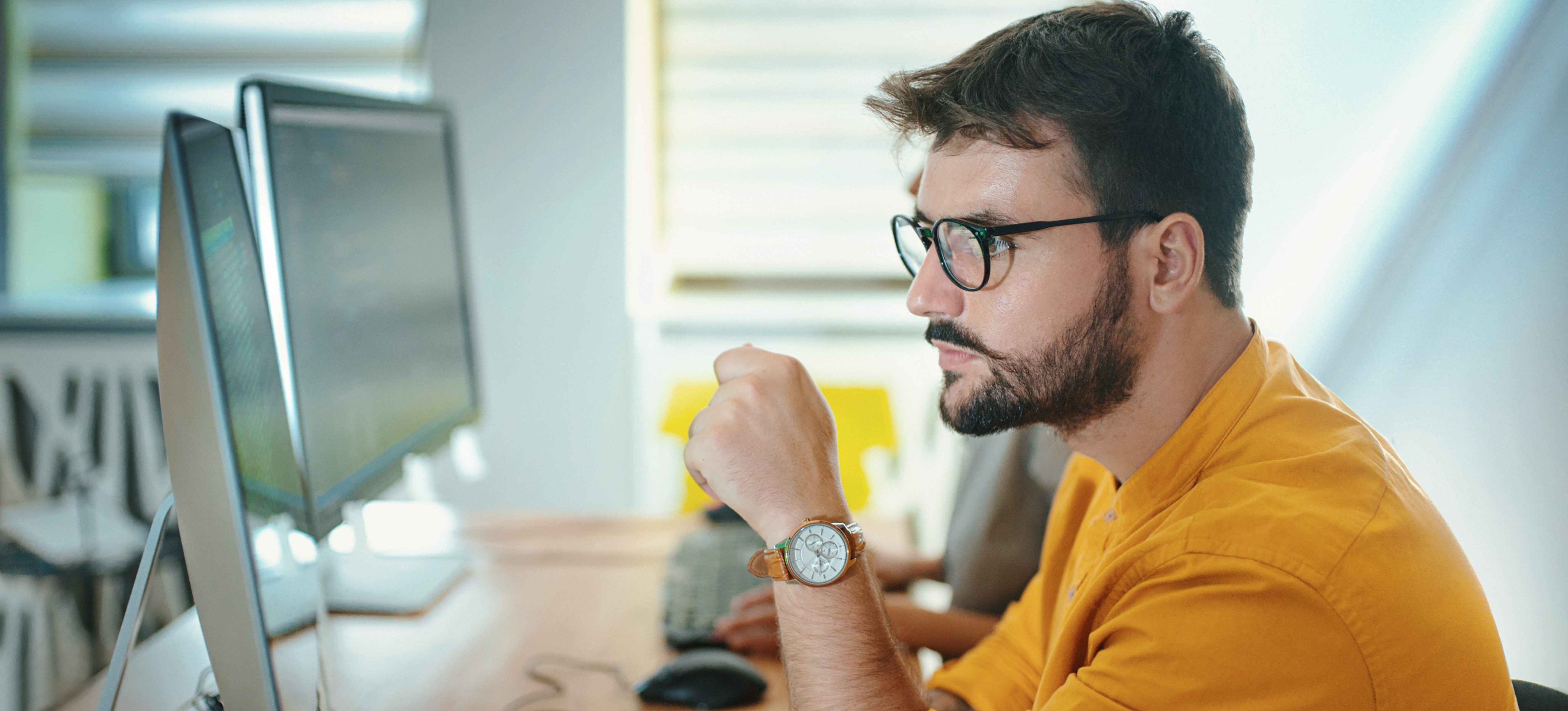 [Featured Image] A web designer works on a development project on their desktop computer. 
