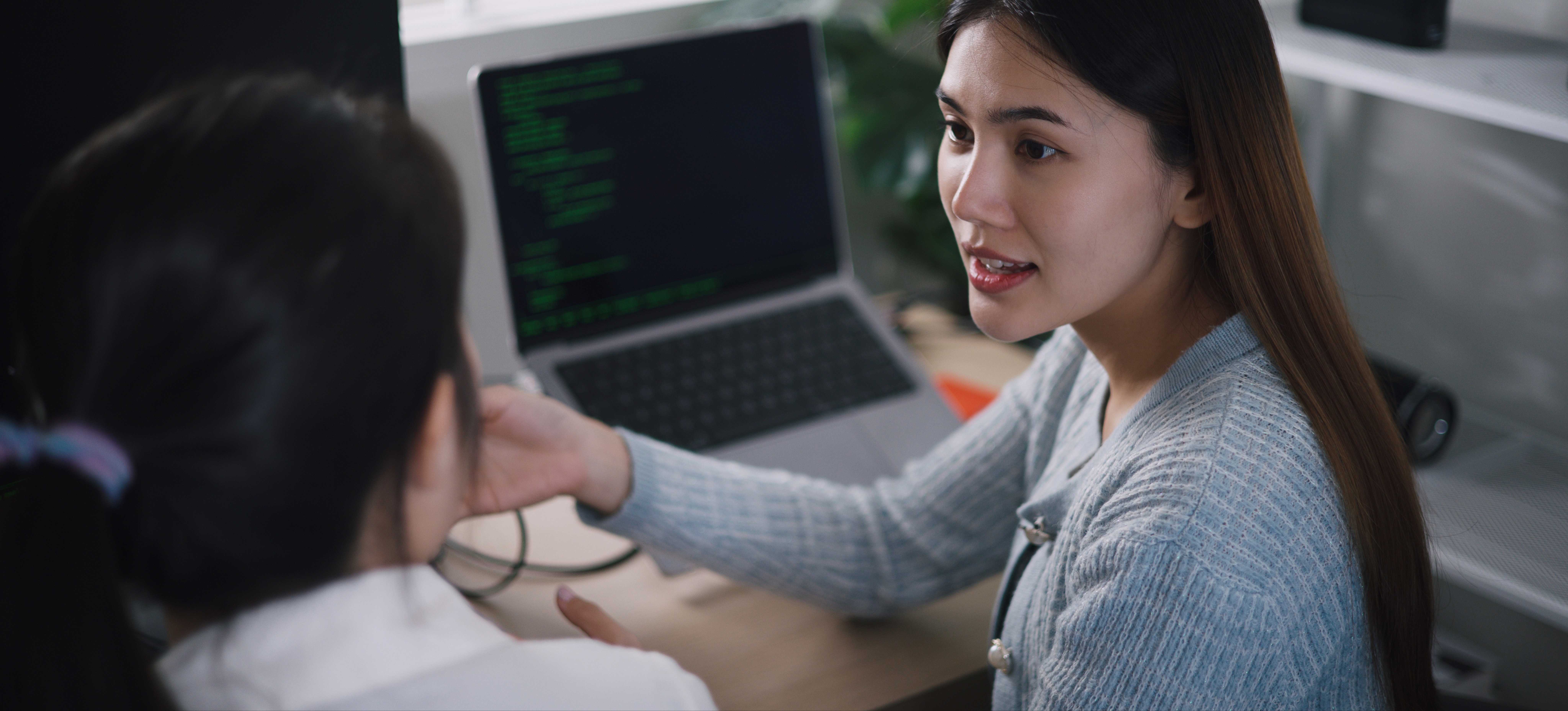 [Featured Image] JavaScript specialists in a workspace, interacting and discussing the topic while reviewing JavaScript code on their computers.