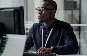 [Featured image] A cybersecurity analyst researches new cybersecurity threats on a desktop computer in an office.