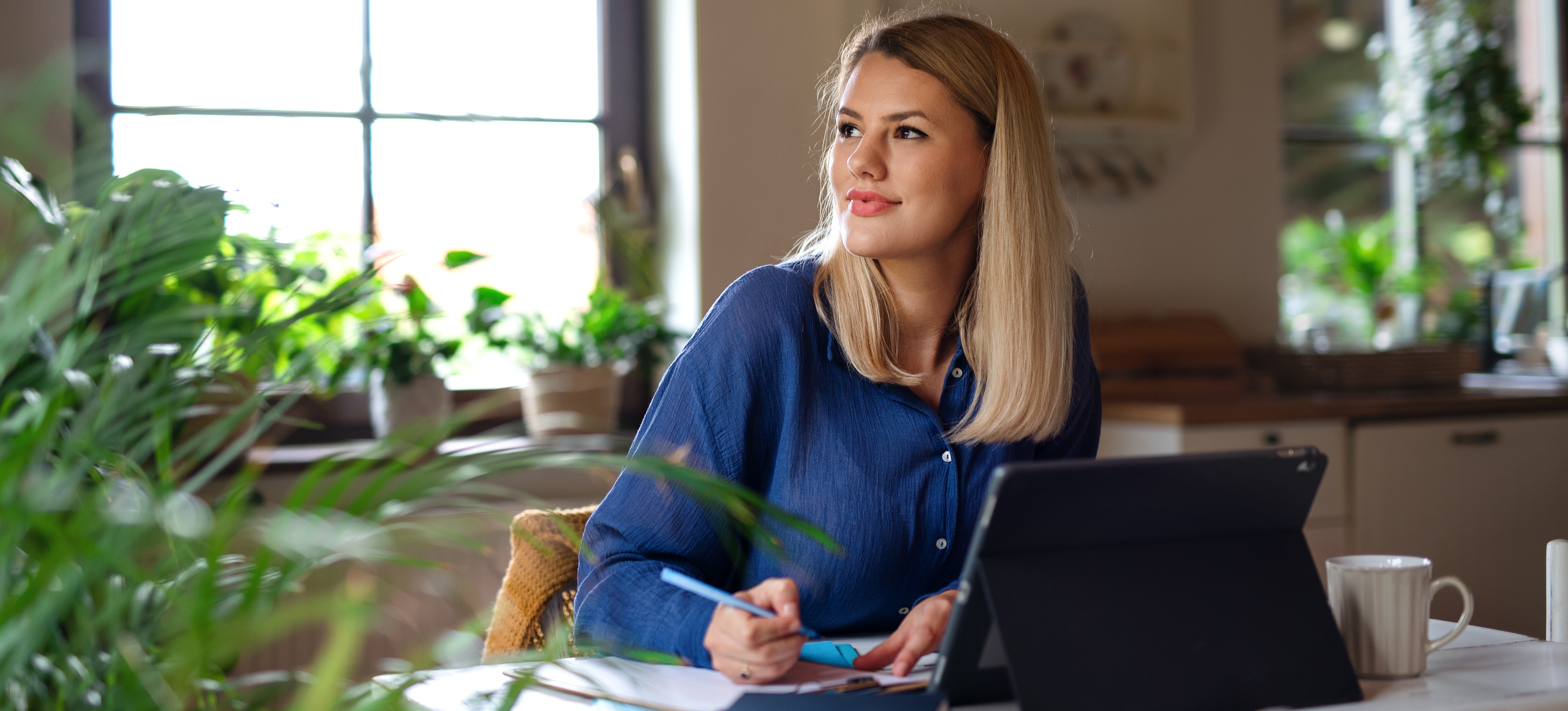 [Featured Image] A job seeker sits in her kitchen with a laptop and paperwork while learning about the proper CV format. 