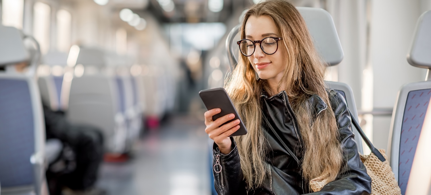 [Featured image] A young person on a train looks at their phone, researching how to transfer colleges.