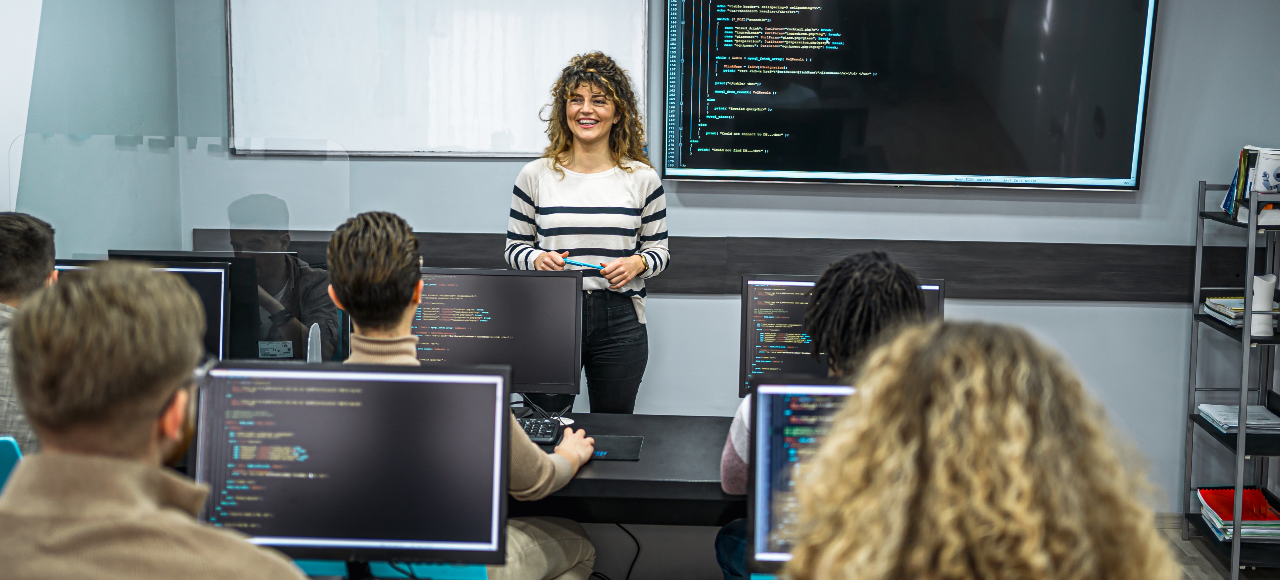 [Featured Image] A programming instructor teaching C++ in a classroom, guiding students through coding concepts.