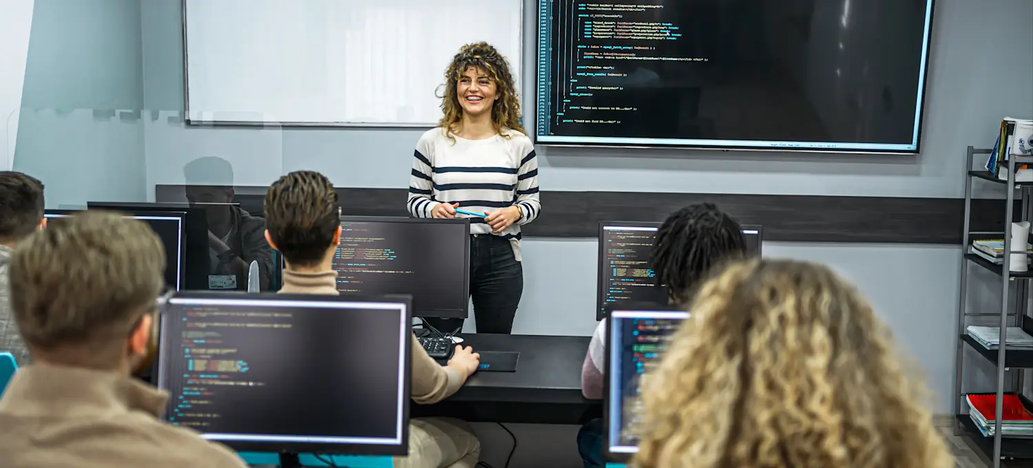 [Featured Image] A programming instructor teaching C++ in a classroom, guiding students through coding concepts.