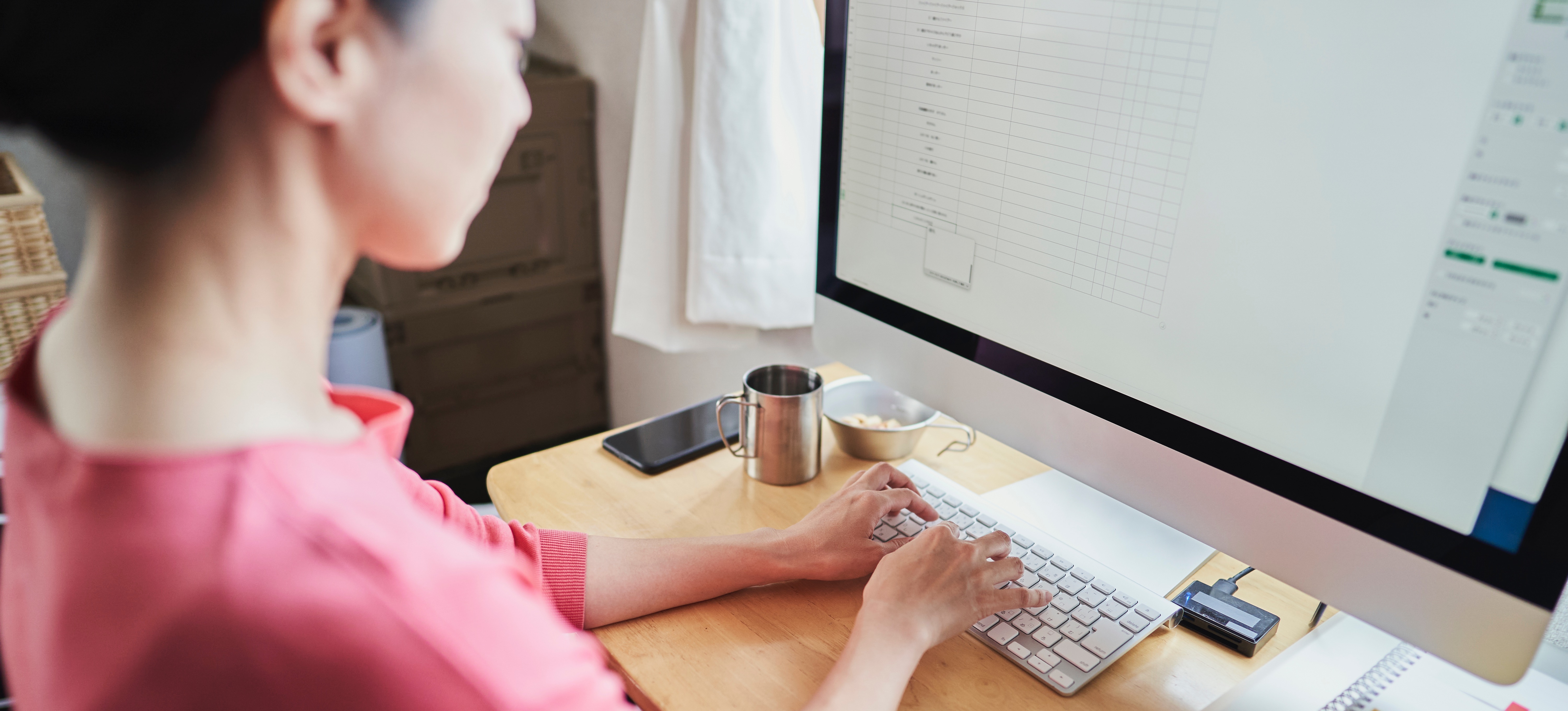 [Featured Image] A person sits at their computer, typing on a wireless keyboard, using Google Sheets API.
