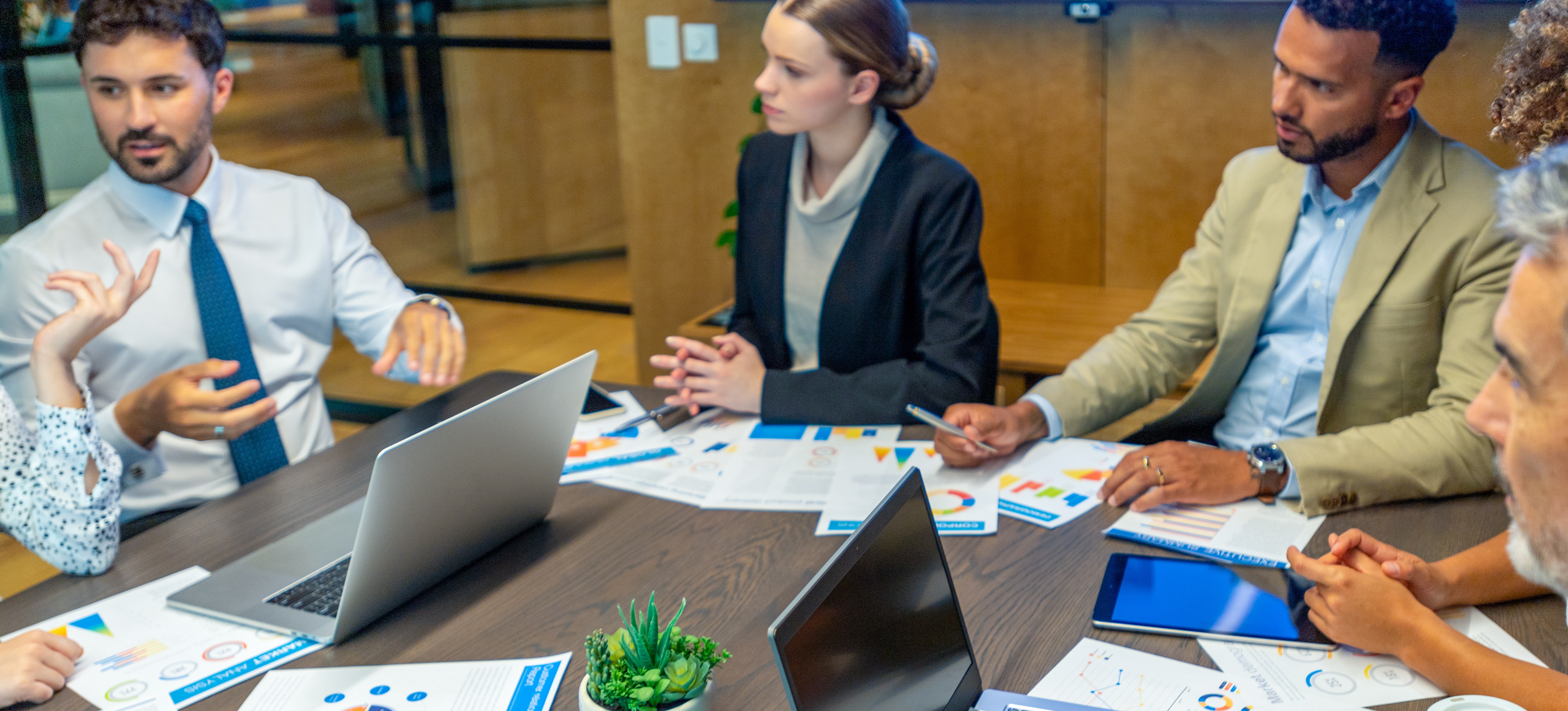 [Hauptbild] Ein Marketingteam sitzt am Konferenztisch mit Laptops und Whiteboards, um die 4 Ps des Marketings zu besprechen.
