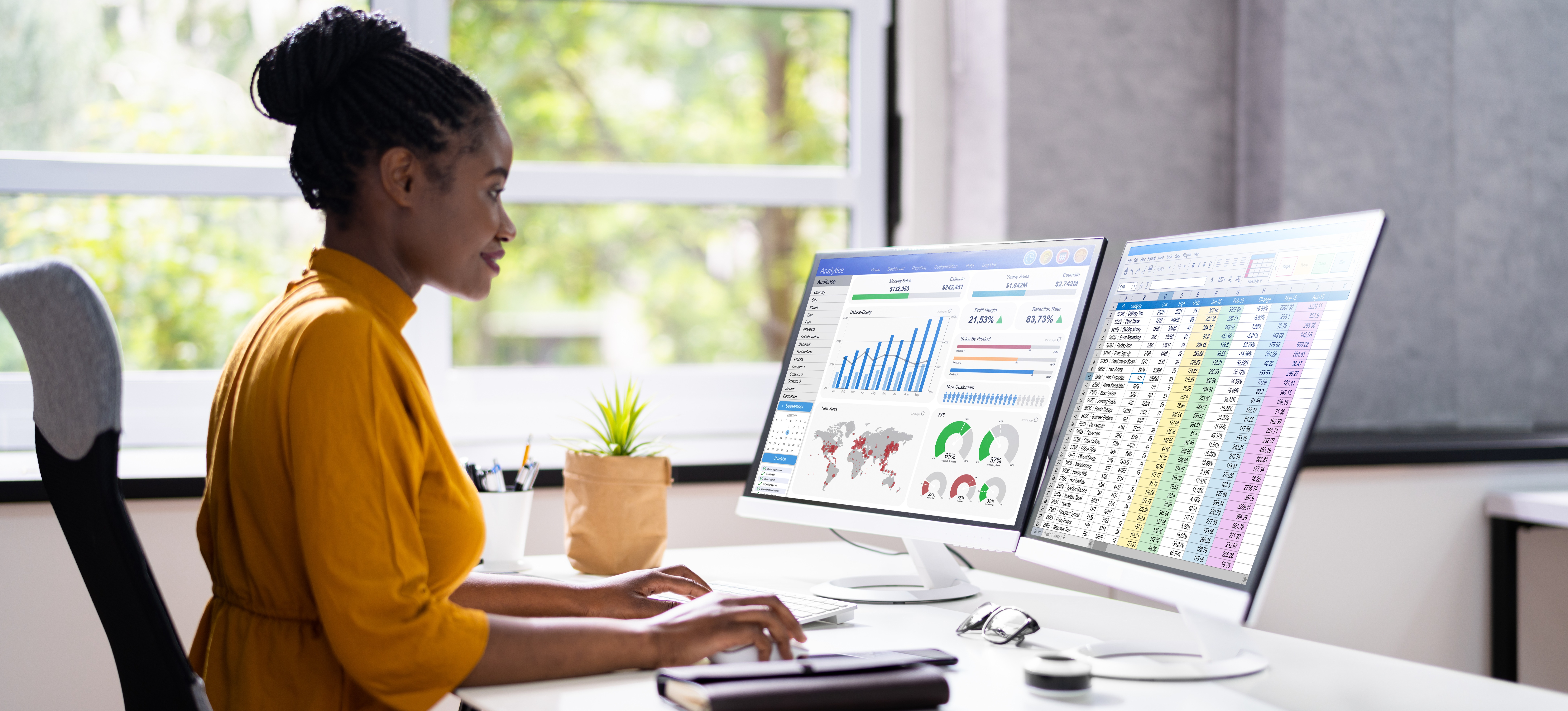 [Featured image] Professional in yellow looking at a dual-screen and reviewing data analysis in a sunny office.

