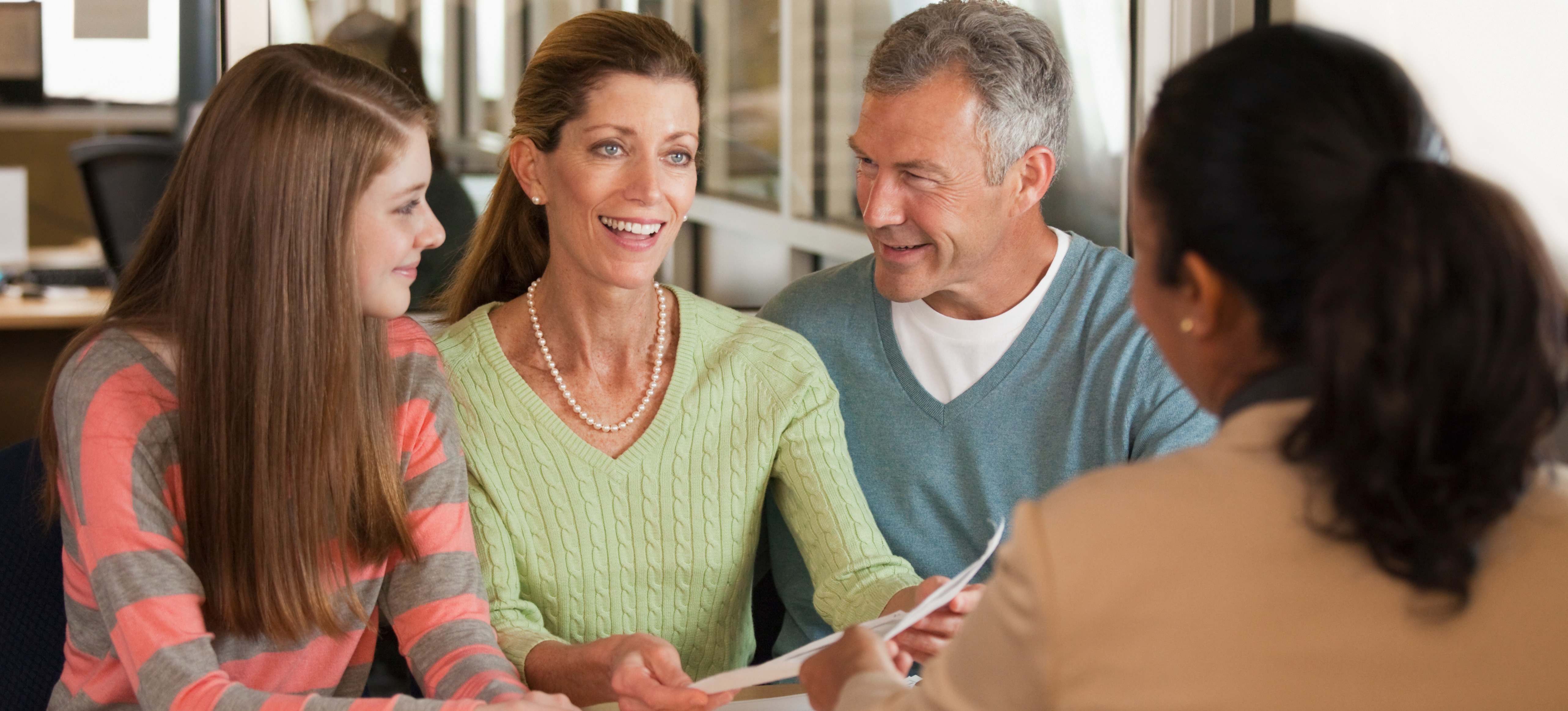 [Featured Image] A high school student and her parents are talking to a college counselor about colleges that accept low GPAs.
