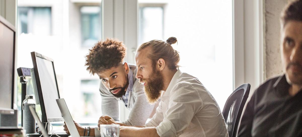 [Feature Image] Two entry-level computer professionals research DevOps engineer salary details as they plan their career paths.
