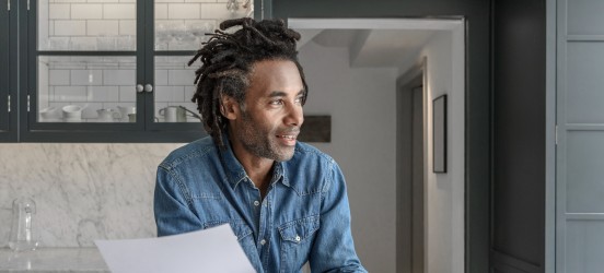 [Featured image] A businessman holds paperwork as he works from home.