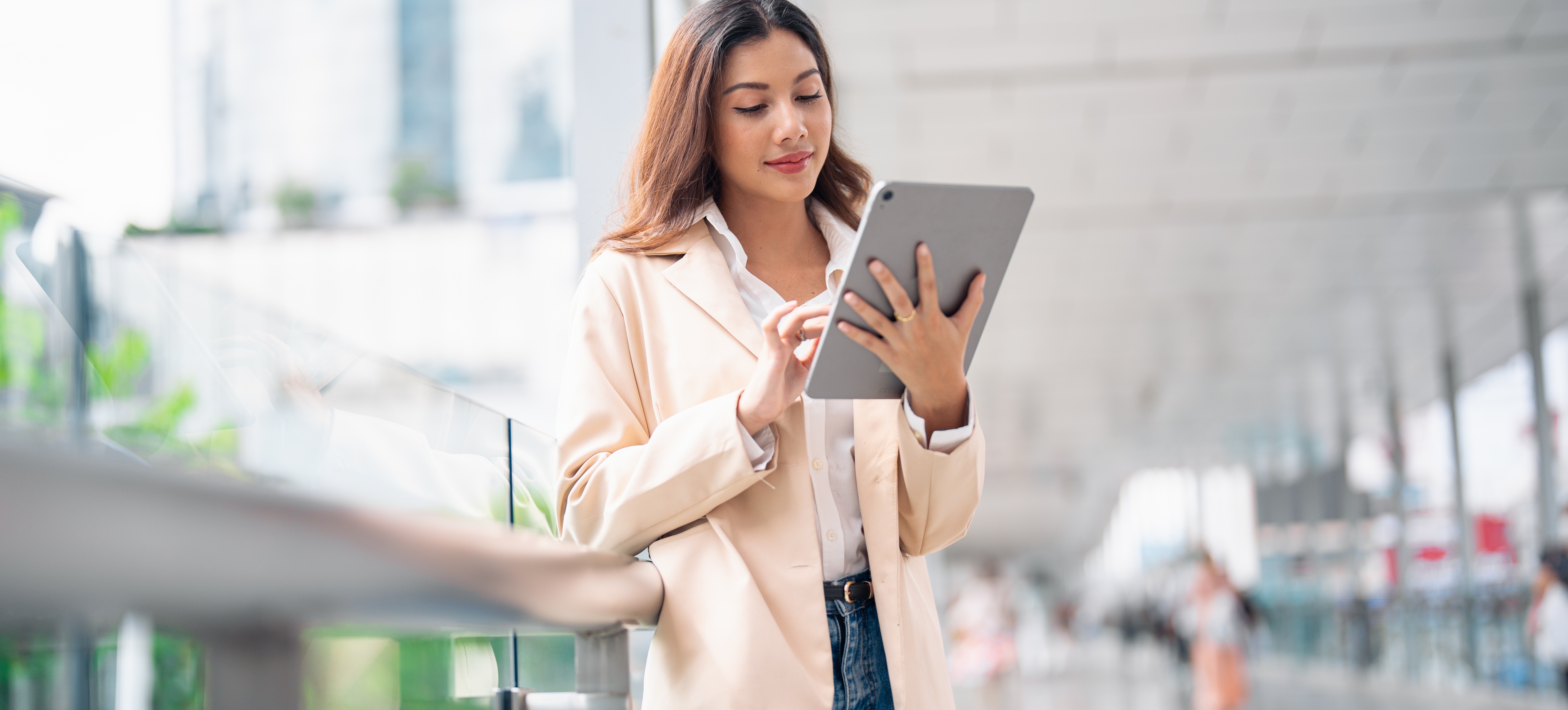 [Featured Image] A person stands outside their office building and uses a tablet to download Google Sheets for a project. 