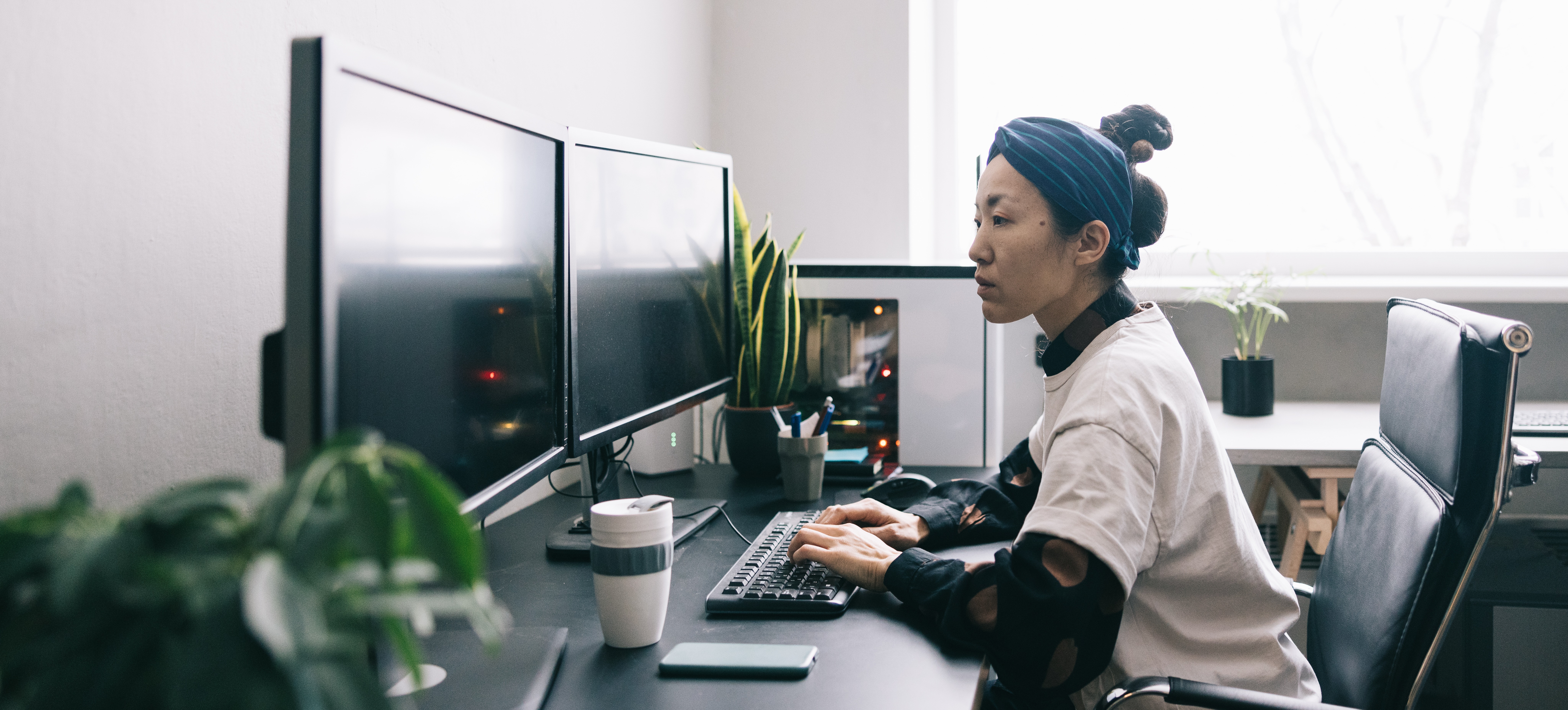 [Featured Image] A DevOps engineer types on their computer and looks at their dual monitors as they update software coding.
