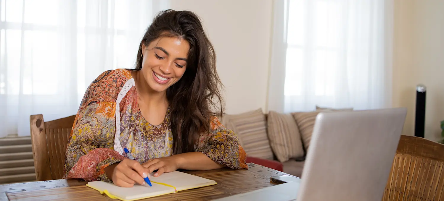 [Featured Image] A professional working from home, taking notes in a notebook while researching the value of online certificates.