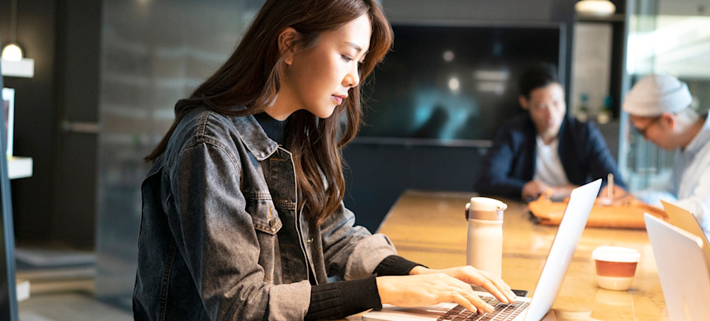 [Featured Image] A person sitting in a cafe, looking up IT certifications on their laptop.
