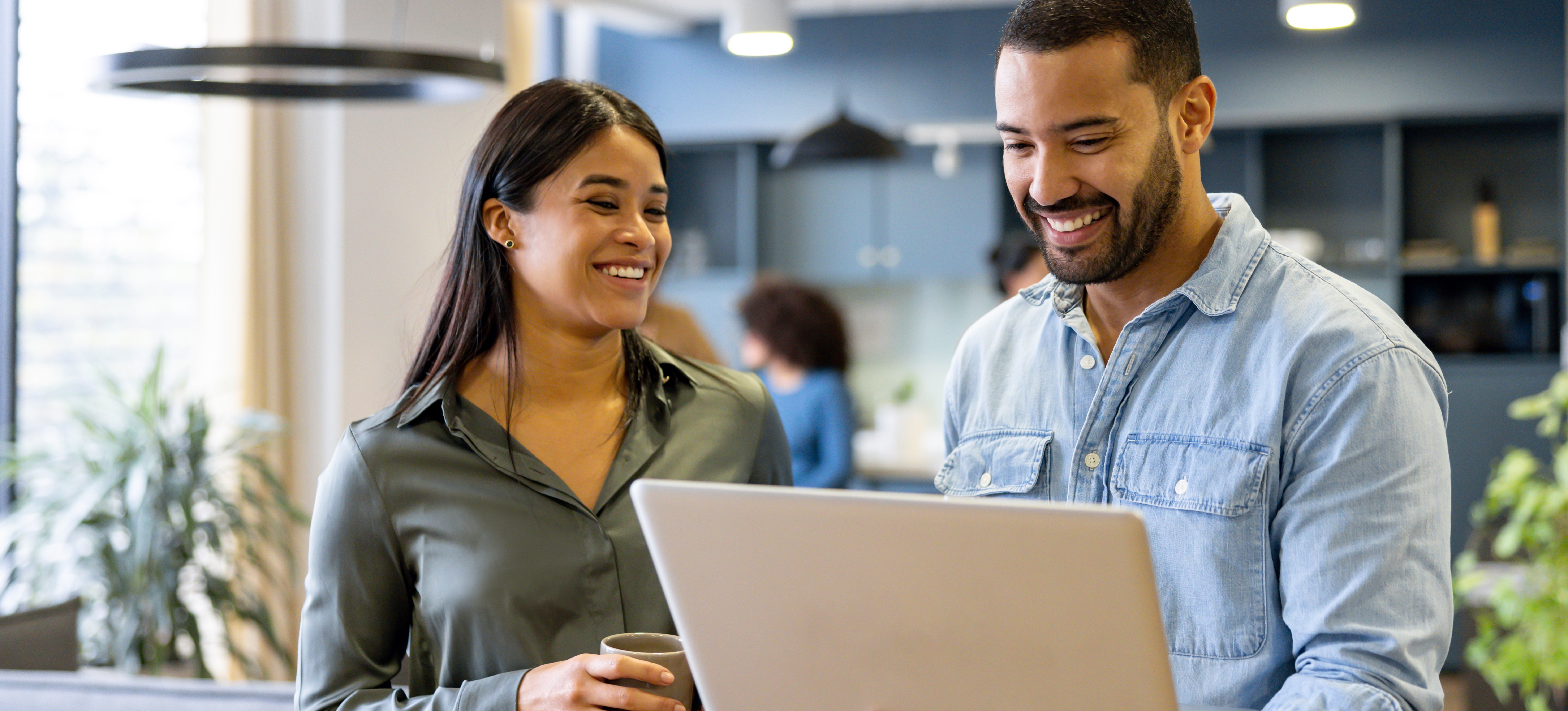 [Feature Image]: A smart contract developer shows an employee they’re mentoring part of their development process on a laptop computer while standing in a professional office environment.
