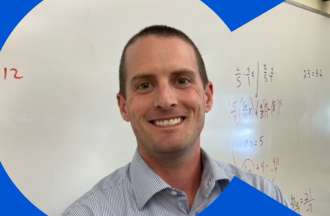 [Featured image] Brendan McKiernan stands smiling in front of a classroom whiteboard. 