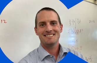 [Featured image] Brendan McKiernan stands smiling in front of a classroom whiteboard. 