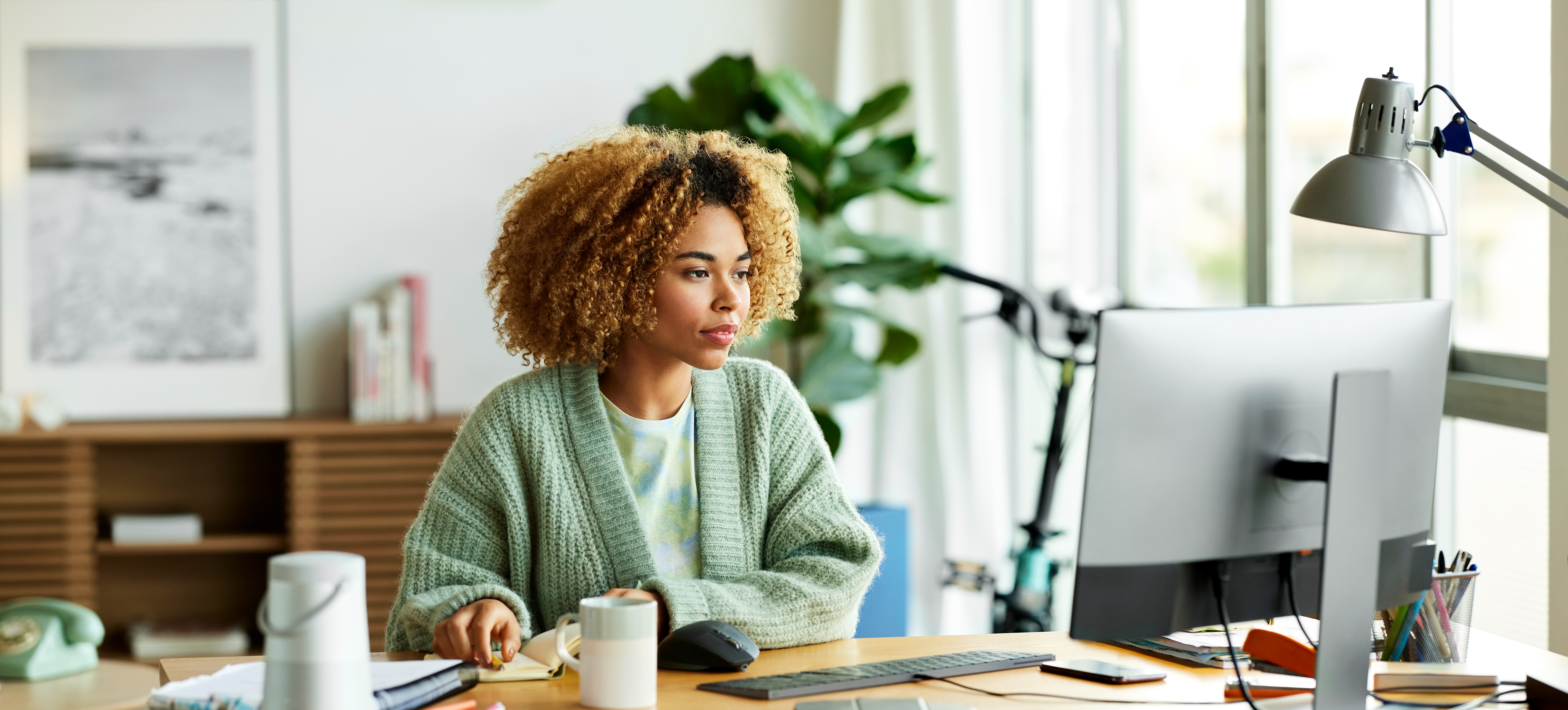 [Featured Image] A women is sitting at her desk in her office. She is focused on her HTML project on her computer.