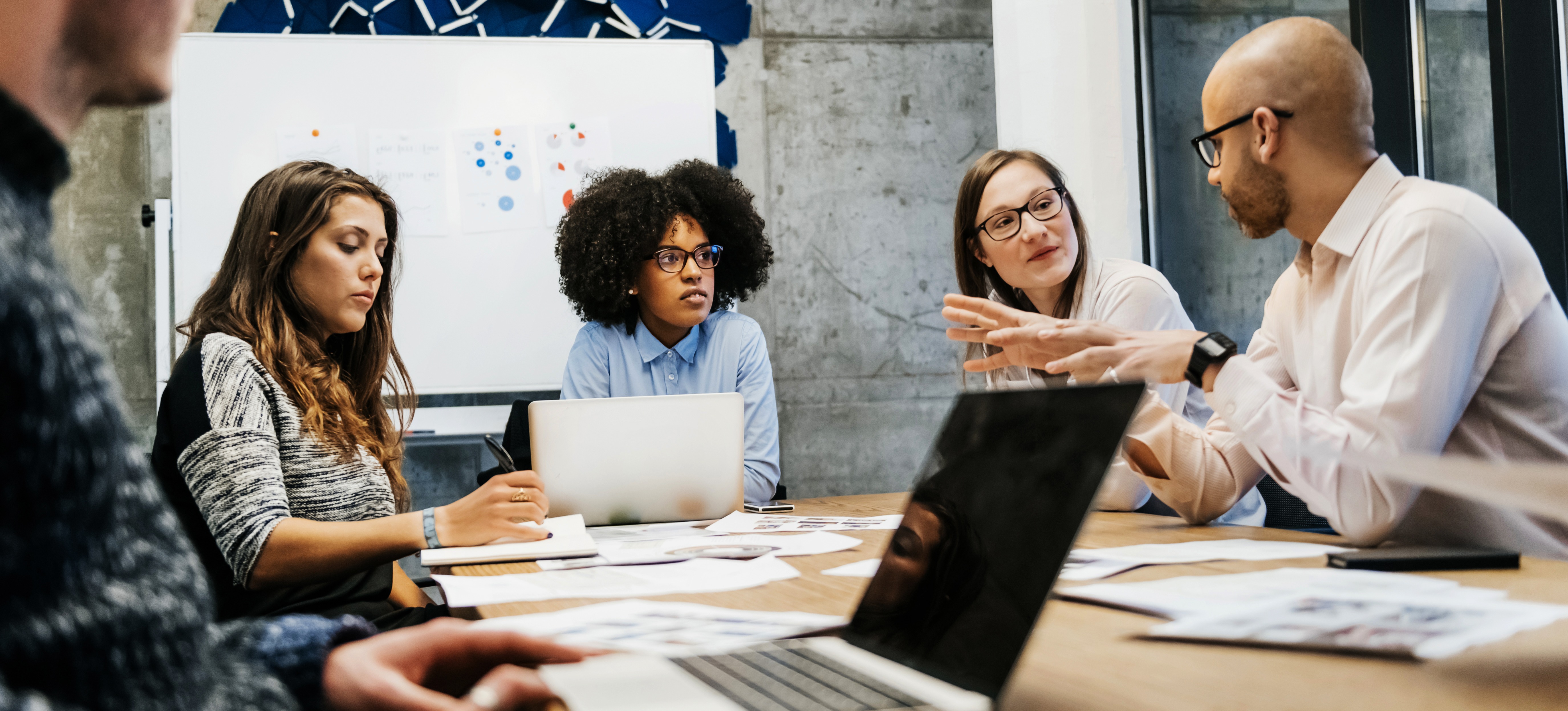 [Featured Image] A company's risk management team is meeting to ensure a smooth transition with their operations.