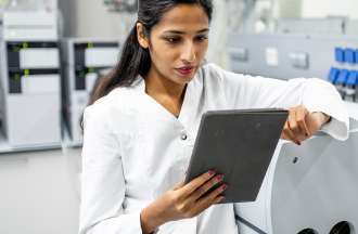 [Featured Image] A scientist in a lab uses a tablet to look at neural networks and identify chemical compounds.  