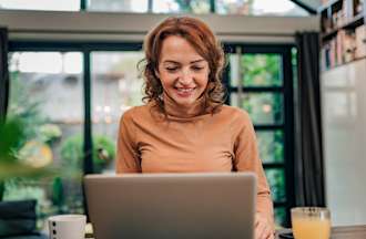 [Featured image] A woman wearing an orange turtleneck sits at home in front of her laptop working on a job application email.