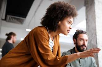 [Featured Image] Two IT colleagues collaborate on an infrastructure project on a shared monitor.