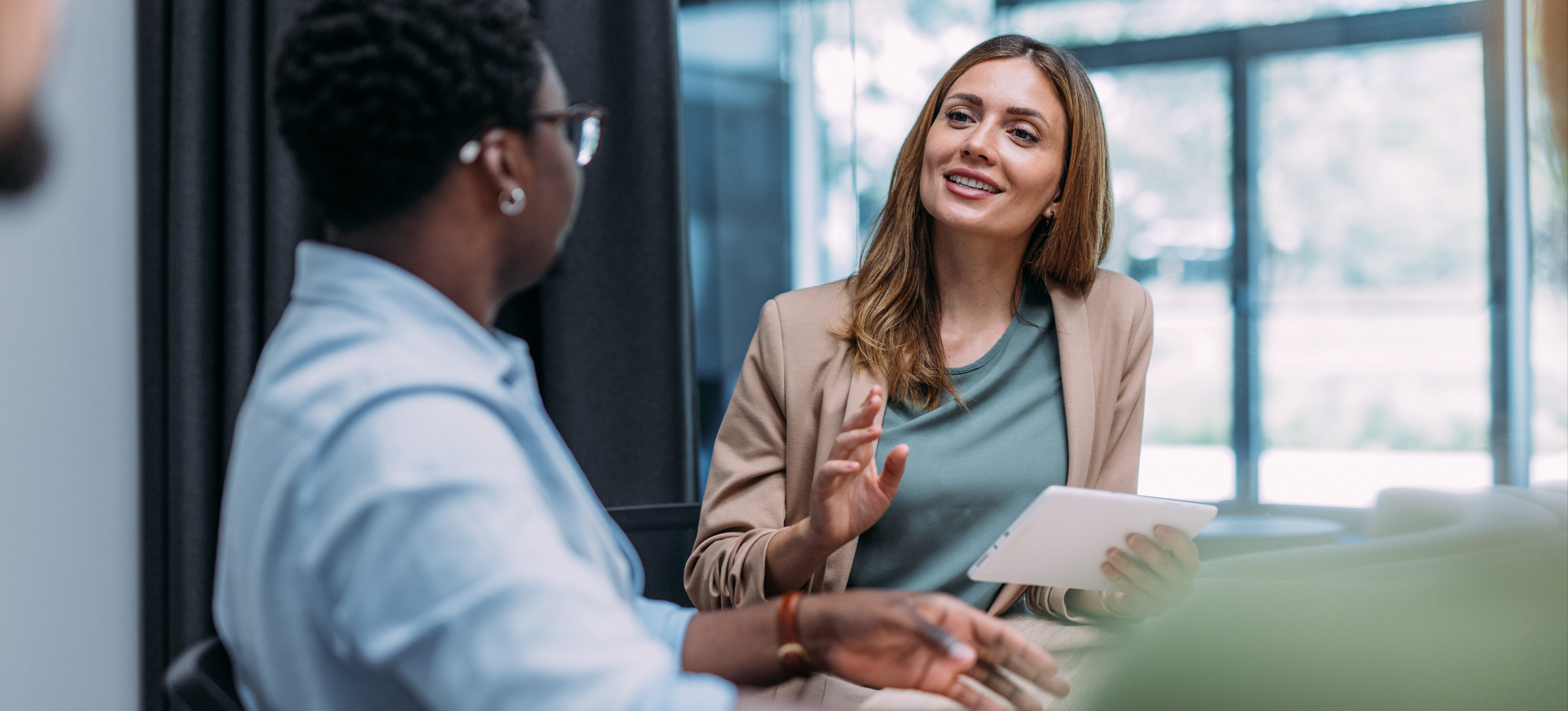[Image en vedette] Un professionnel des ressources humaines fait preuve d'un leadership efficace en discutant joyeusement avec un employé alors qu'ils sont tous deux assis dans un bureau bien éclairé.