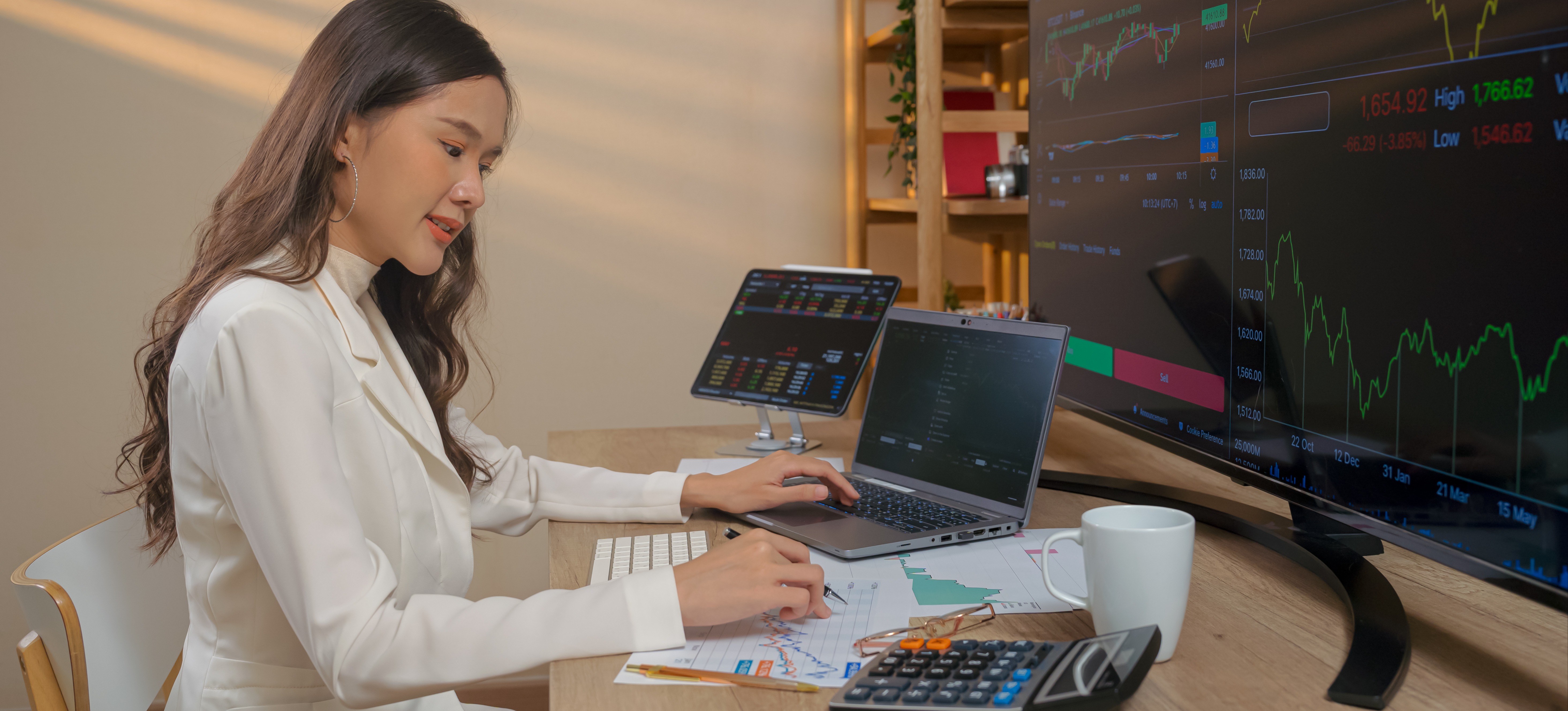 [Featured Image] A business professional is sitting at their desk with multiple monitors displaying graphs and trends created using DAX to analyze their data. 
