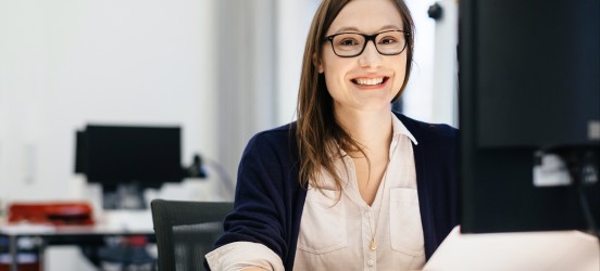 [Featured image] An accounts payable employee sits at a desktop computer.