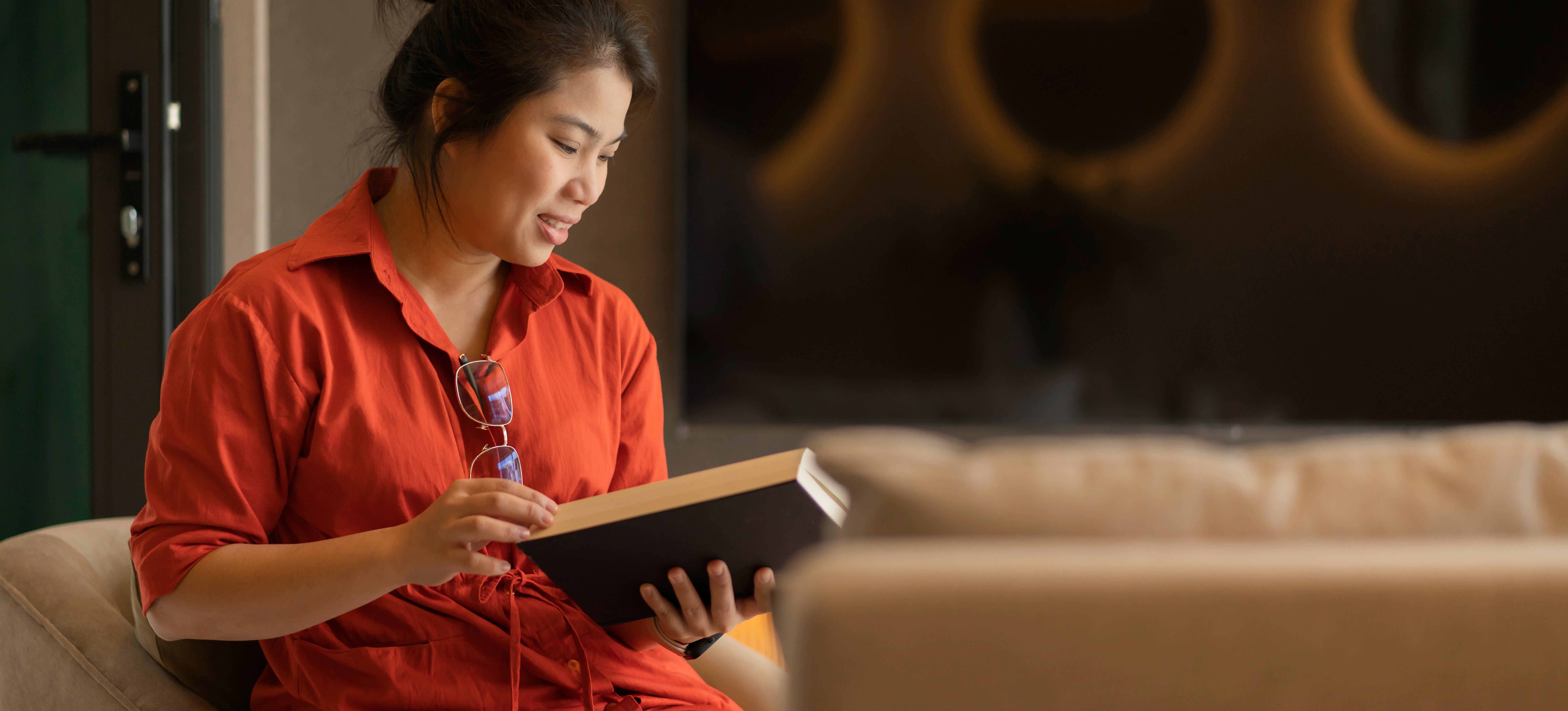 [Featured Image] A learner sits in their living room reading a book and contemplating if they should pursue a graduate certificate or a master's degree.