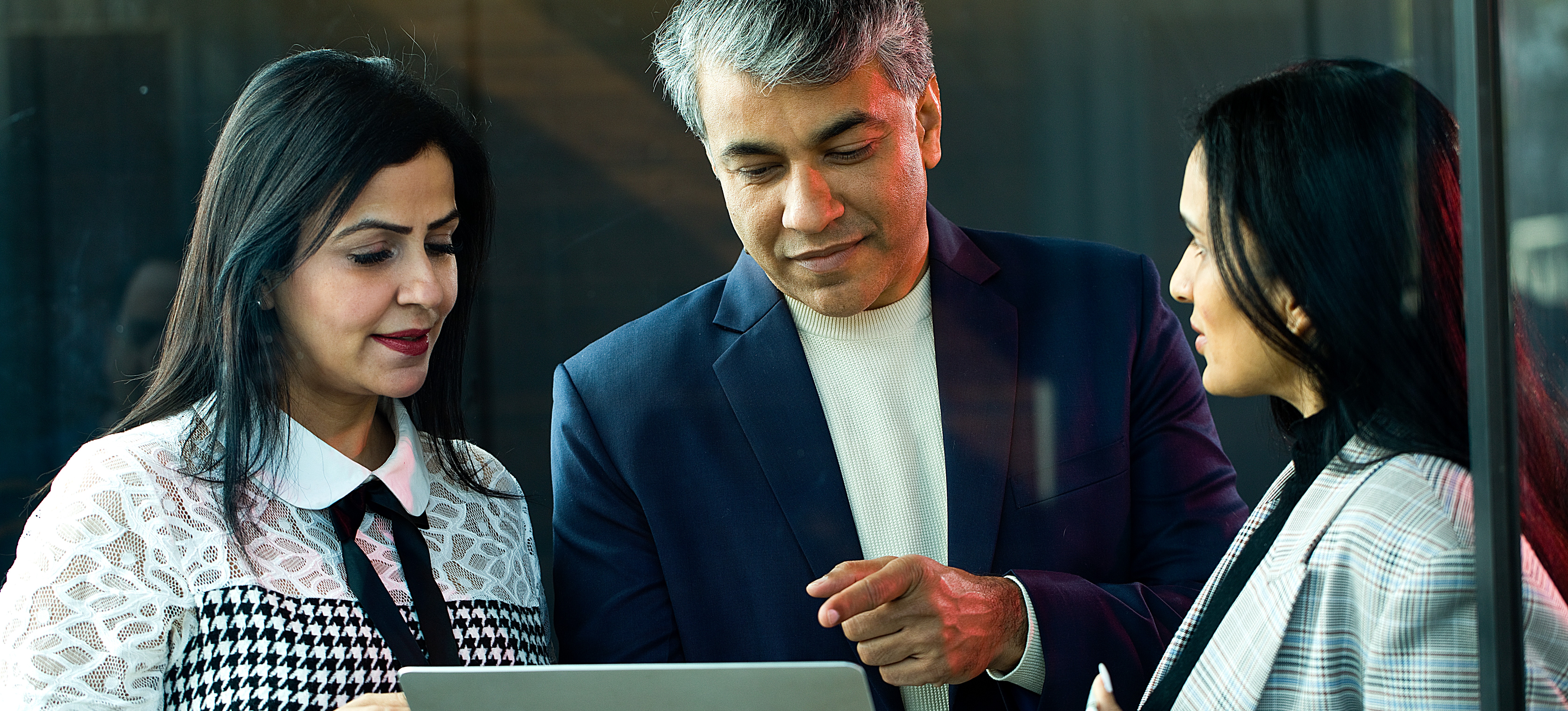 [Featured Image]: Three people look at a laptop while one of them explains what is UX strategty for an upcoming project.
